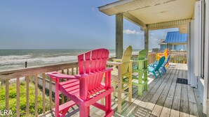 Un pontile in legno con poltrone Adirondack colorate che si affaccia sull'oceano.