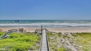 Una passerella di legno che conduce a una spiaggia, con vista limpida sull'oceano.
