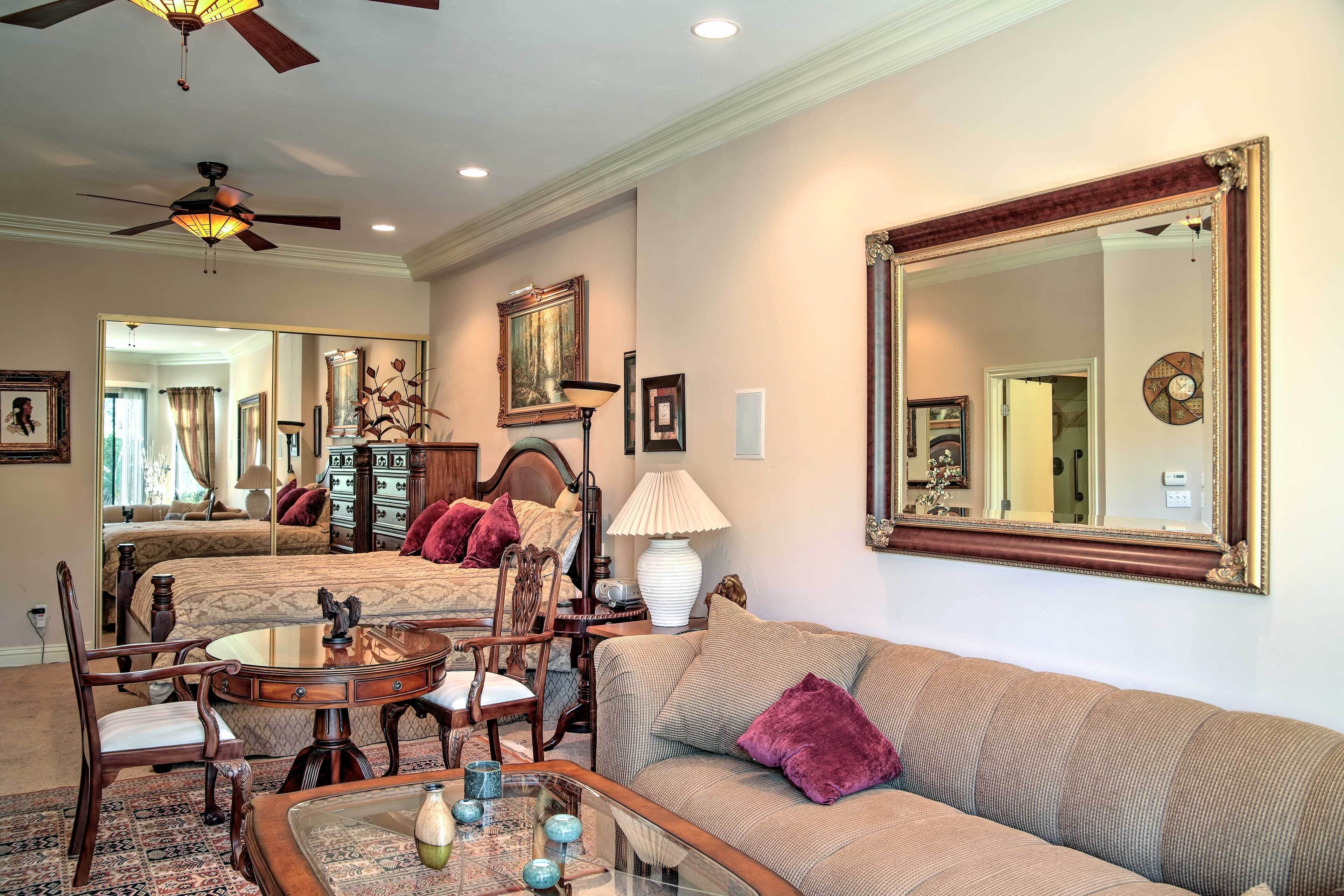 A well-furnished living room with a sofa, armchair, dining table, and a ceiling fan.
