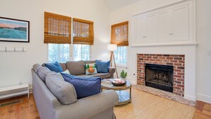 A living room with a sofa, a fireplace, and a large window with blinds. - Enchanting Andersonville Home Steps to Norris Lake (Andersonville)