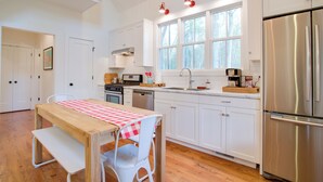 A modern kitchen with white cabinets, a stainless steel refrigerator, and a wooden table with a checkered tablecloth. - Enchanting Andersonville Home Steps to Norris Lake (Andersonville)