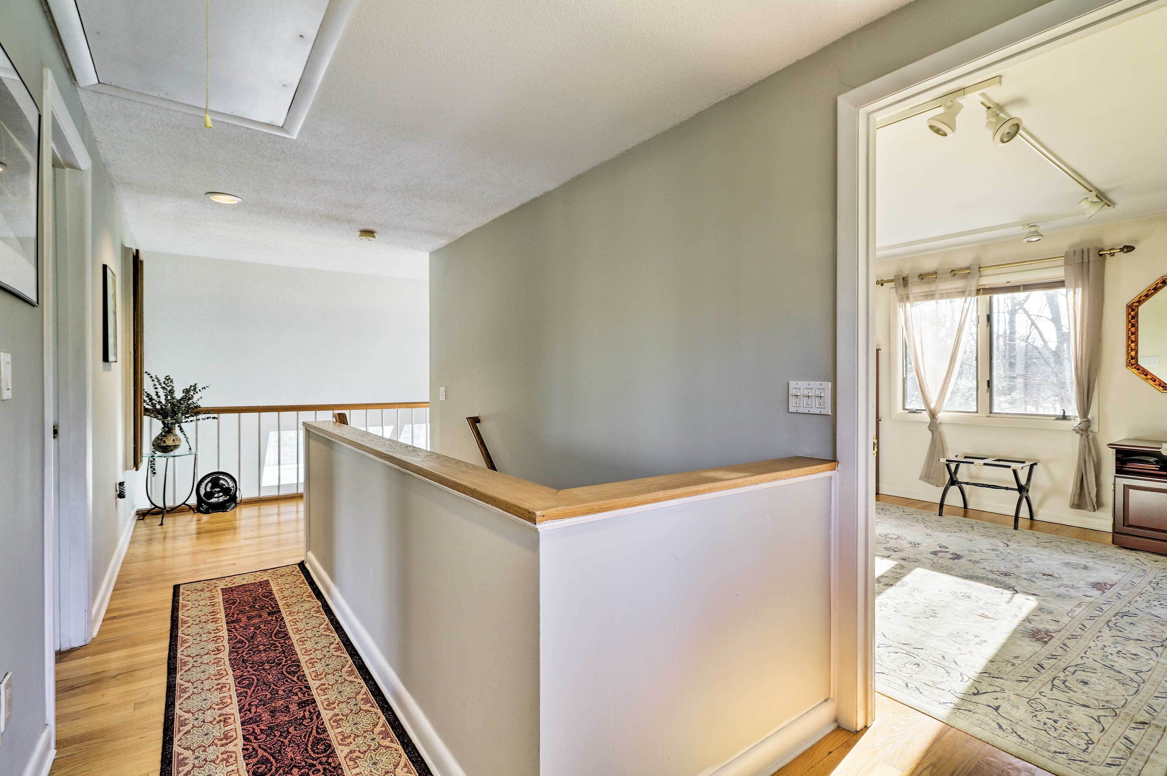 A modern interior with a wooden reception desk, a patterned rug, and a view of a window with curtains.