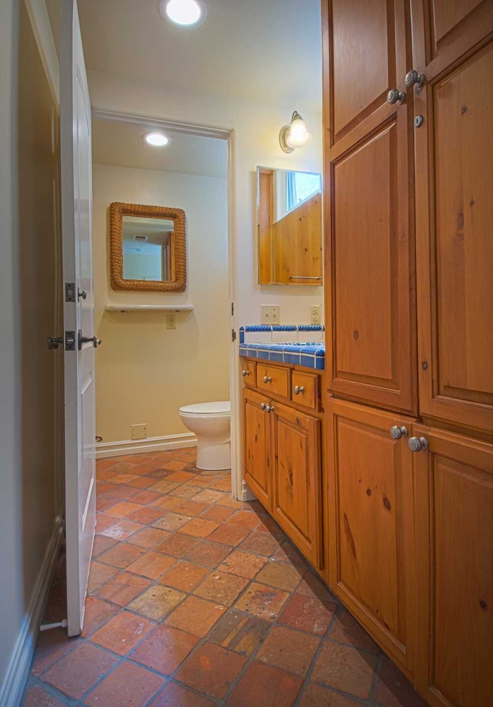 A bathroom with a toilet, a mirror, and wooden cabinets.