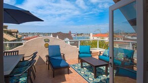 A terrace with outdoor furniture, a patterned rug, and a view of a coastal town. - Beautiful, bright and charming 3-story townhouse on an amazing street in Newport! (Newport Beach)