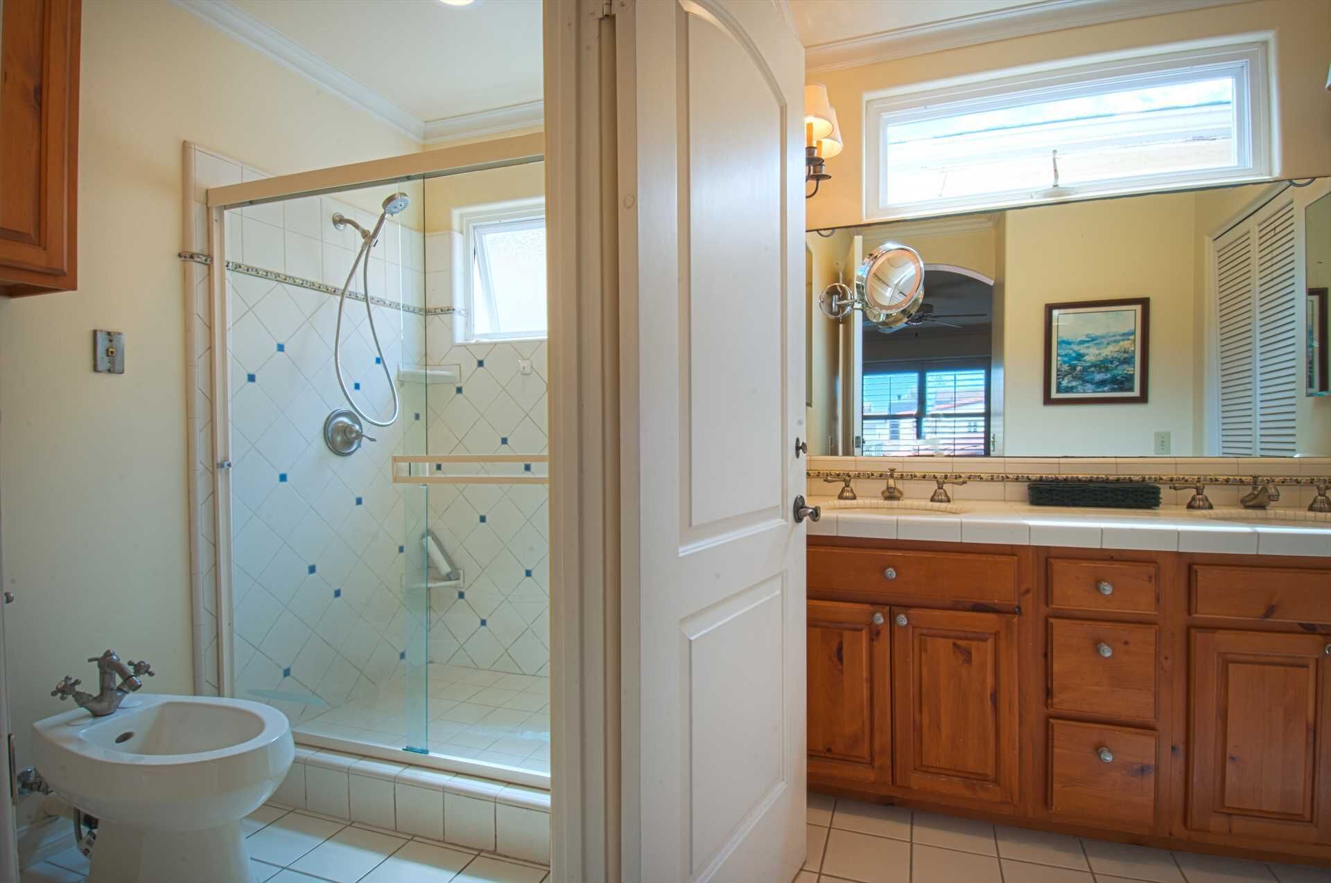 Une salle de bain avec une douche à parois de verre, un lavabo, des meubles en bois et un grand miroir.