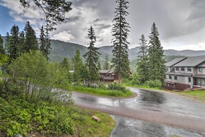 A road curving through a forested area with a lodge and a building in the background. - Rustic Home on Whitefish Mountain, Near Ski Run! (Whitefish)