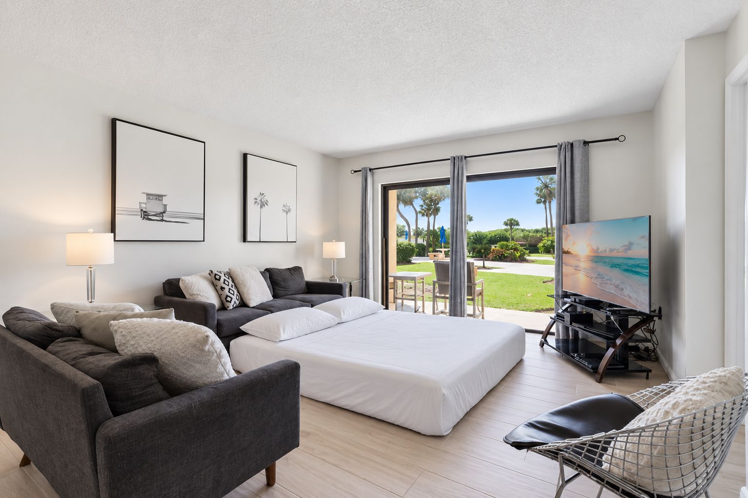 A hotel room with a bed, a sofa, a TV, and a balcony with a view.
