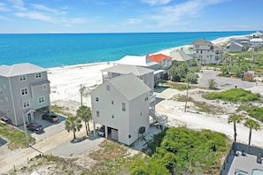 A coastal residential area with beachfront properties, including a two-story house with a garage and a detached house with a red roof.