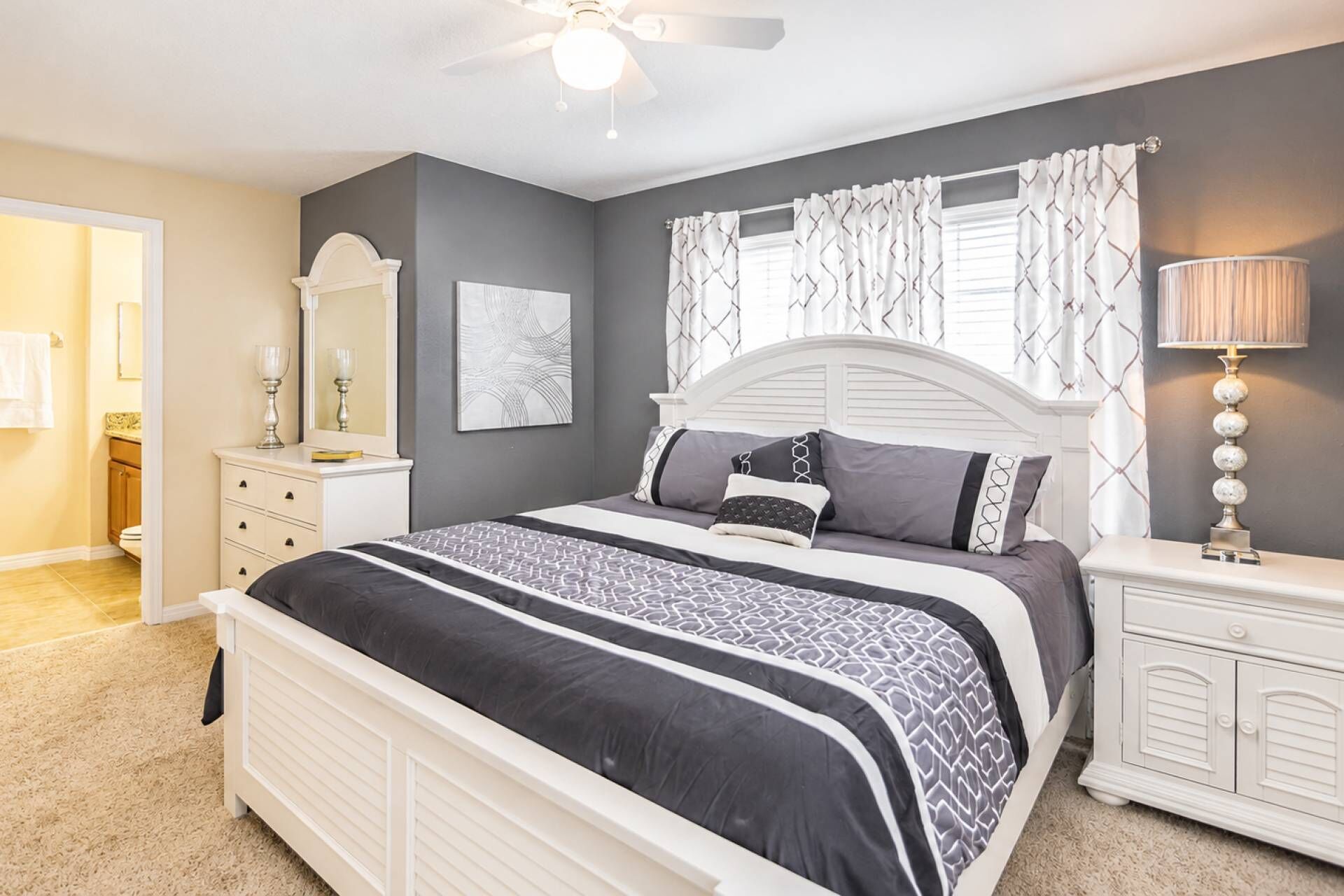 Une chambre à coucher comprenant un lit, une table de chevet, une commode et un ventilateur de plafond.