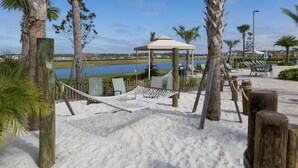 A beach area with a hammock, a gazebo, and a poolside setting. - Storey Lake Resort home with Mini-Golf & Lazy River | Private Pool | Sleeps 10 (Kissimmee)