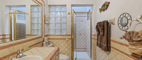 Une salle de bain équipée d’un lavabo, de toilettes, d’une douche et décorée avec un motif de poissons sur le mur.