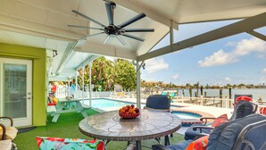 A covered outdoor area with a pool, lounge chairs, and a table with fruit. - Waterfront Getaway w/ Pool & Dock - Walk to Beach! (Indian Rocks Beach)