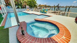 A swimming pool with a hot tub, surrounded by a deck with lounge chairs and a view of the water. - Waterfront Getaway w/ Pool & Dock - Walk to Beach! (Indian Rocks Beach)
