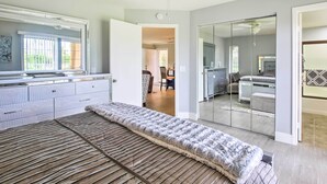 A modern bedroom with a large bed, a ceiling fan, and a sliding glass door leading to a bathroom. - Pool & Hot Tub Access: Modern Palm Springs Condo (Palm Springs)