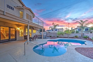 Una propiedad residencial con piscina, un patio cubierto y una casa de dos pisos con balcón.
