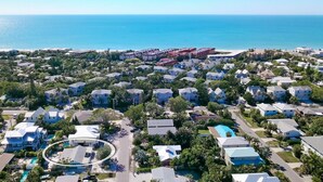 Et kystnære boligområde med huse, en swimmingpool og en strand i baggrunden.