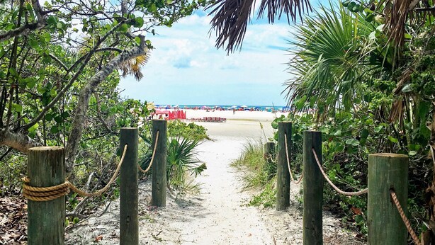A sandy pathway leading to a beach with wooden posts and ropes on either side. - Condo# 221 2B/2B End garden unit with partial pool views: fans in all bedrooms (Sarasota)