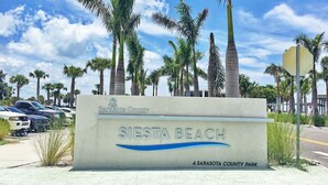 A sign for Sarasota County Park, indicating a park area with a parking lot and palm trees in the background. - Condo# 221 2B/2B End garden unit with partial pool views: fans in all bedrooms (Sarasota)