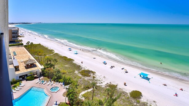 A beach resort with a swimming pool, beach umbrellas, and a view of the ocean. - Views from Beachfront Balcony ~ Pool ~ Updated    Fantastic Location Near Shops Bars and Restaurants (Madeira Beach)