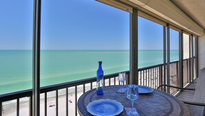 A balcony with a view of the ocean, a table with plates and a bottle, and a glass. - Views from Beachfront Balcony ~ Pool ~ Updated    Fantastic Location Near Shops Bars and Restaurants (Madeira Beach)
