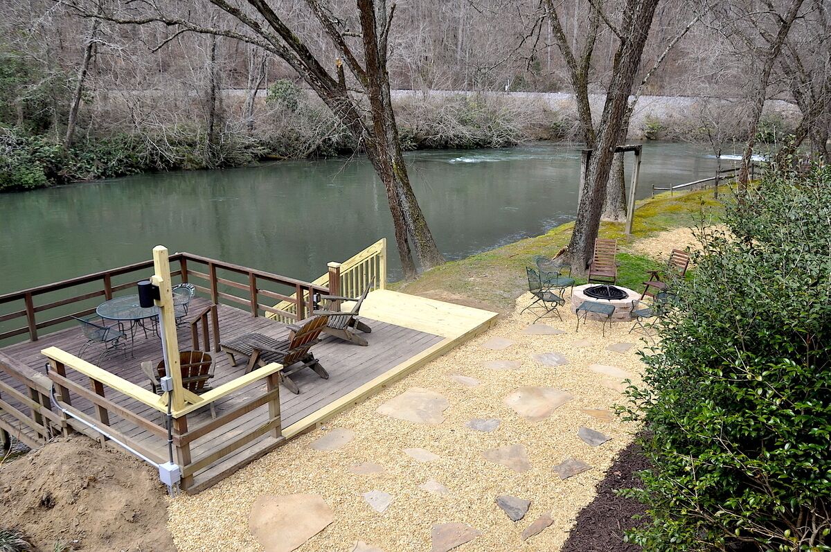 A deck with outdoor furniture overlooking a river.