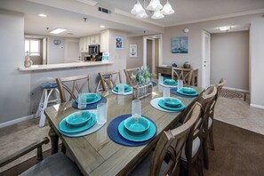 A dining area with a wooden table set for six, surrounded by chairs.