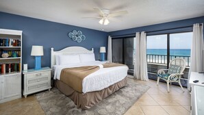 Una camera da letto con un letto, un comodino, una libreria, una sedia e vista sull'oceano.