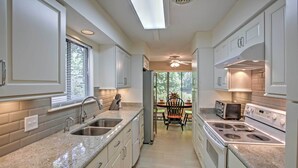 A kitchen with white cabinets, granite countertops, a built-in oven, and a dining area with a table and chairs. - Charming Hilton Head Home on Quiet Street (Hilton Head Island)