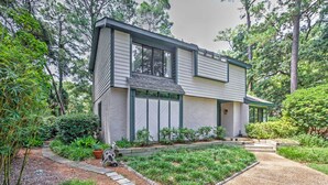A modern two-story house with a sloped roof, large windows, and a well-maintained garden with a pathway leading to the entrance. - Charming Hilton Head Home on Quiet Street (Hilton Head Island)
