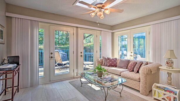 A spacious living room with a glass coffee table, a beige sofa, and a ceiling fan. - Charming Hilton Head Home on Quiet Street (Hilton Head Island)