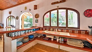 A kitchen with a wooden countertop, a sink, and decorative plates on the wall.