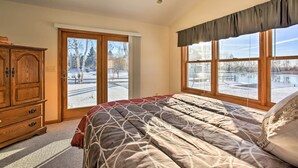 Un dormitorio con una cama grande, un aparador de madera y una ventana con vistas a un paisaje nevado.