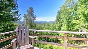 Eine Holzterrasse mit Blick auf einen Wald und Berge.