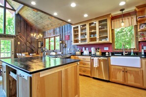 Une cuisine avec des meubles en bois, un grand îlot central et une vue sur l’extérieur.