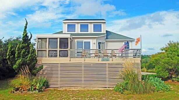 A two-story house with a balcony, a flag, and a view of the surrounding landscape. - WH974- Huge Private Pool, only 500 Feet To Beach, Basketball, & Dog Friendly! (Corolla)