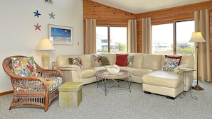 A cozy living room with a sofa, armchairs, a small coffee table, and a floor lamp. There are star decorations on the wall and a window with curtains. - WH974- Huge Private Pool, only 500 Feet To Beach, Basketball, & Dog Friendly! (Corolla)