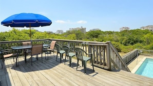 A wooden deck with outdoor furniture, a blue umbrella, and a pool. - WH974- Huge Private Pool, only 500 Feet To Beach, Basketball, & Dog Friendly! (Corolla)