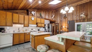 Una cocina con armarios de madera, una isla central y un área de comedor con taburetes.