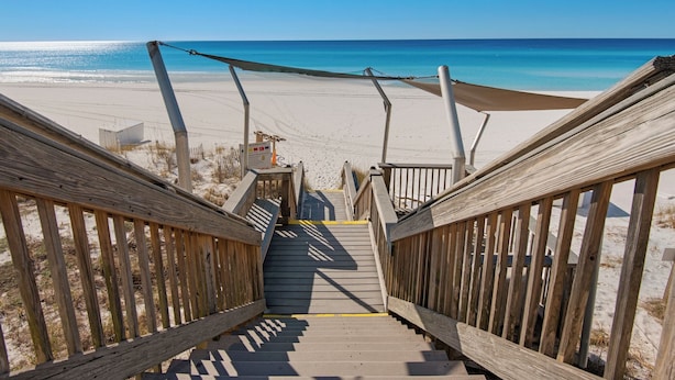 Eine Holztreppe führt zu einem Strand mit freiem Blick auf das Meer.