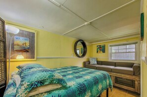 Une pièce comprenant un lit, un canapé, une fenêtre, un miroir et un mur orné d’un tableau.