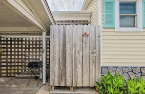 A wooden fence, a grill, and a house with a window.