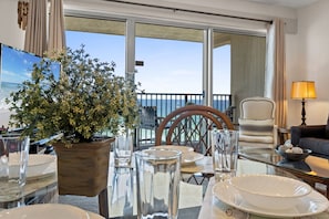 Enjoy a meal with a view of the sea from this dining area, featuring a glass table and comfortable seating.