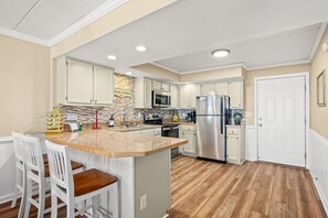 Una cocina moderna con armarios blancos, encimera de granito y electrodomésticos de acero inoxidable.