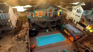 A large two-story house with a pool, multiple balconies, and a deck area.