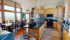 A spacious kitchen with wooden cabinets, a large island, and a view of the ocean.