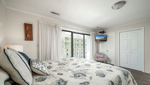 Un dormitorio con una cama grande, un televisor, vistas a edificios y un letrero que dice "Beach Aloha".