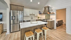 Una cocina moderna con una isla grande, electrodomésticos de acero inoxidable y taburetes de madera.