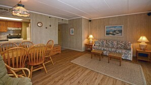 Un salon comprenant un coin repas, un plancher en bois, un canapé et un tableau accroché au mur.