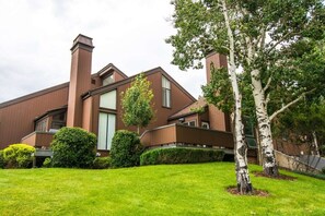 A modern two-story house with a well-maintained lawn and mature trees.