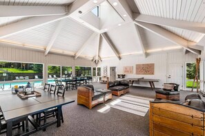 A spacious indoor area with a high ceiling, a pool visible through large windows, and a seating area with leather sofas and a dining table. - Three Kings 1 at Park City Mountain (Park City)